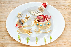 Funny pancakes Santa Claus and reindeer ride in a sleigh , creative idea for Christmas breakfast