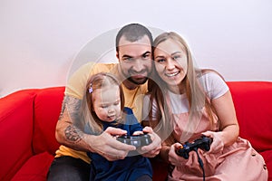 Funny parents and child girl sit playing video games