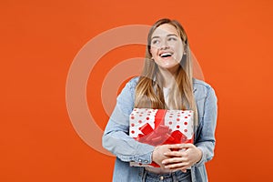 Funny pensive young woman girl in casual denim clothes isolated on orange background. Valentine`s Day Women`s Day