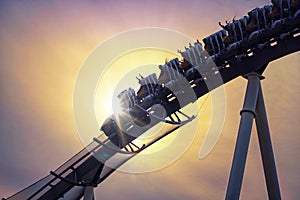 Funny people riding roller coaster with sun light