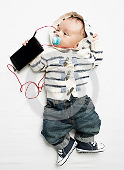 Funny photo of baby boy listening to music on phone with earphones