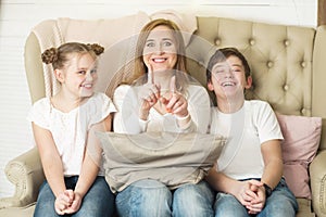 Funny photo session of a mother with two children sitting on the couch