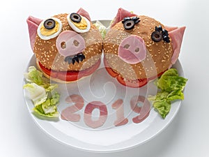 Funny piggies new year ham burgers, lettuce salad and 2019 digits on the plate