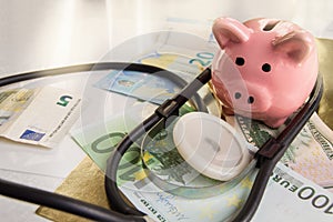 Funny piggybank, standing on dollars and euros with a phonendoscope. Saving hospital savings and investing in medicine