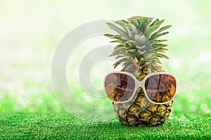 Funny Pineapple with white sunglasses on green grass background