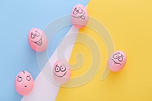Funny pink eggs with face feeling on colorful background