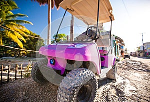 Funny pink golf car in the street on a tropical