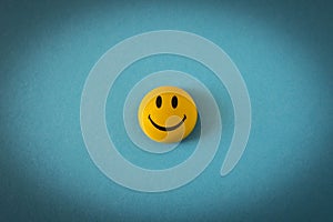 Funny plastic smiley face on a blue background. The concept of a positive mood