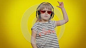 Funny playful blonde child kid listening music via headphones dancing disco fooling having fun party