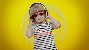 Funny playful blonde child kid listening music via headphones dancing disco fooling having fun party