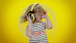 Funny playful blonde kid child girl listening music via headphones, dancing disco fooling having fun