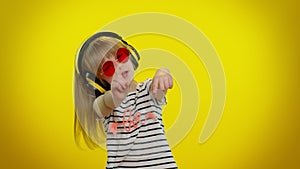 Funny playful blonde kid child girl listening music via headphones, dancing disco fooling having fun