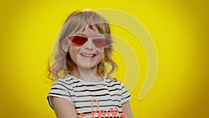 Funny playful blonde kid child wearing sunglasses, blinking eye, looking with charming smile