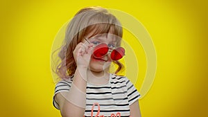 Funny playful blonde kid child wearing sunglasses, blinking eye, looking with charming smile