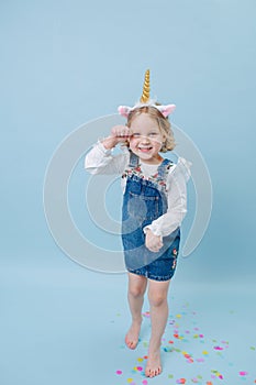 Funny playful little girl in unicorn head band over blue background