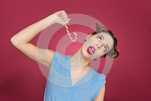 Funny playful young woman having fun with candy cane