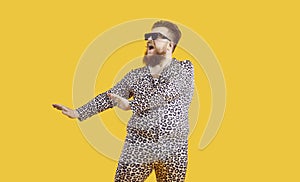 Funny plus size man in sunglasses and leopard PJs dancing and singing in fashion studio