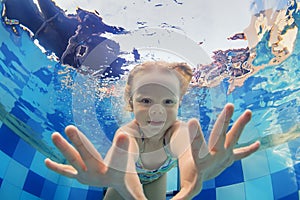 Funny portrait of baby girl swimming underwater in pool