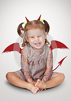 Funny portrait of bad child with tatoo and devil horns, disobedi