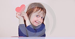 Funny portrait of cute little child girl with red heart as symbol of love and amorousness