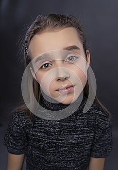 Funny portrait of a cute smiling teen girl wearing a dark turtleneck. Gray background. Advertising, trendy and commercial design.