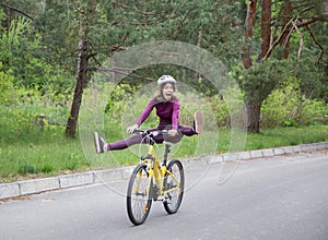 Funny portrait of an emotional girl in a helmet on a bicycle in motion