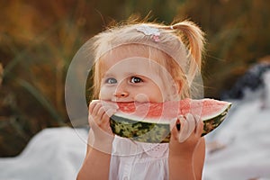 Funny portrait of an incredibly beautiful little girl eating watermelon on a hot summer day. portrait