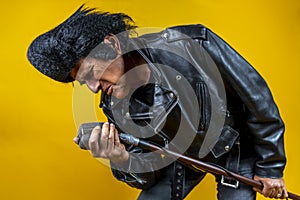 Funny portrait of mature rocker. An old singer dressed in rockabilly style in action