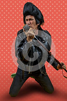 Funny portrait of mature rocker. An old singer dressed in rockabilly style in action