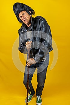 Funny portrait of mature rocker. An old singer dressed in rockabilly style in action