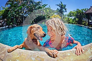 Funny portrait of smiley woman with dog in swimming pool