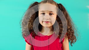 Funny portrait on a turquoise background of a happy little smiling girl looking at the camera Cute baby with a cute face