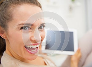 Funny portrait of woman sitting on divan and using tablet pc