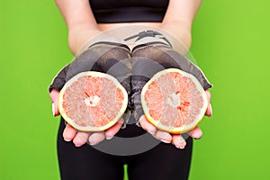 Funny portrait of young brunette fitness woman holding fresh pink grapefruit. Healthy eating lifestyle and weight loss concept.