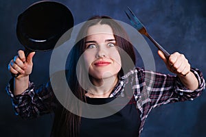 Funny portrait of young enthusiastic housewife with frying pan a