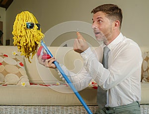 Funny portrait of young weird crazy and happy man holding mop with sunglasses as if it was his fiance kneeling and proposing marri