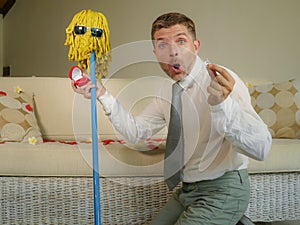 Funny portrait of young weird crazy and happy man holding mop with sunglasses as if it was his fiance kneeling and proposing marri