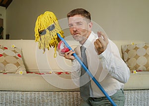 Funny portrait of young weird crazy and happy man holding mop with sunglasses as if it was his fiance kneeling and proposing marri