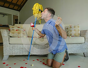 Funny portrait of young weird crazy and happy man holding mop with sunglasses as if it was his fiance kneeling and proposing marri