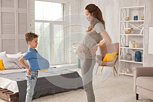 Funny pregnant mother playing games with little son