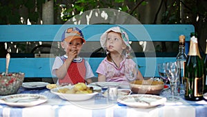 Funny preschool children sitting at a table together and waiting for lunch