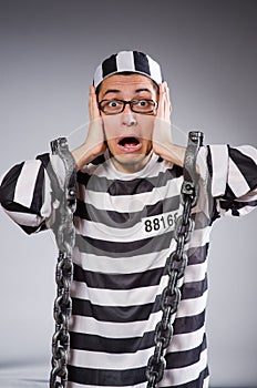 Funny prisoner in chains isolated on gray