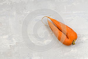 Funny products concept. Ugly carrot on a gray concrete background. Food waste. Top view. copy space