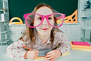 Funny pupil with glasses, home kids schooling. Child boy education concept. Cute pupil in classroom with funny face