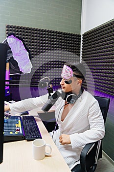 funny radio presenter in sleep mask, bathrobe and cosmetic patches drinking tea
