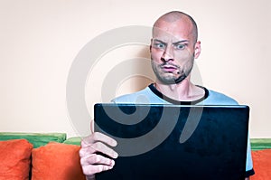 Funny reaction and facial expression of the man who find out online inappropriate content in the pop up message on his laptop comp