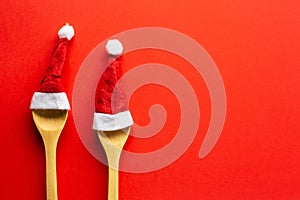 Funny red christmas background with wooden spoon and two red santa hats.