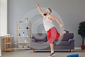 Funny red fat man doing exercises while standing at home.