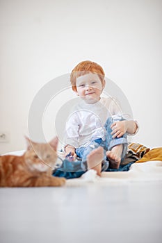 Funny red-haired boy in bed with a red cat
