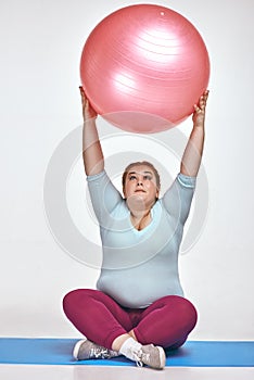 Funny red haired, chubby woman is holding a ball